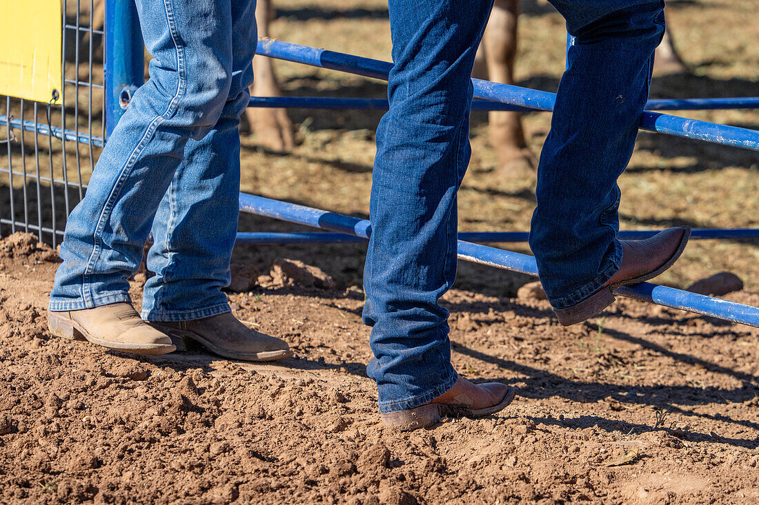 Boots on a couple of cowboys standing by a fence in a rodeo arena in Utah.