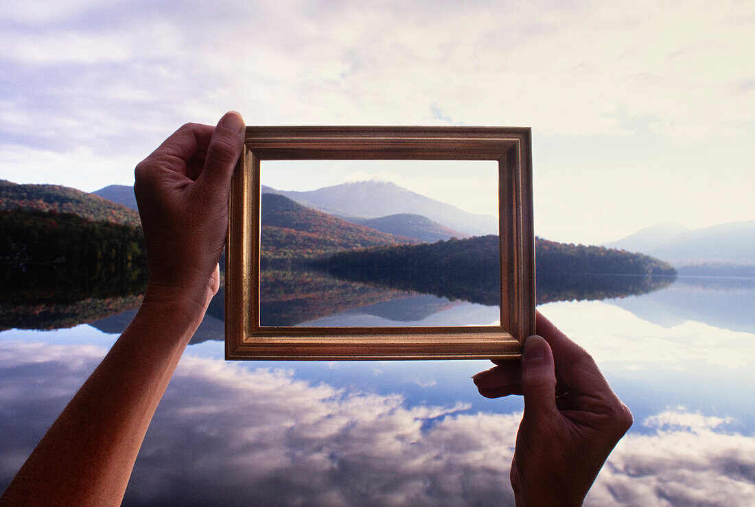 Frauenhände, die einen Bilderrahmen halten, um Lake Placid und die Hügel zu beruhigen