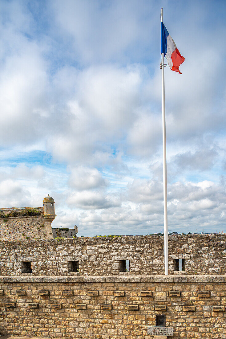 Die französische Flagge weht in Port Louis Citadelle in Lorient, Bretagne, Frankreich. Ein historisches Fort mit malerischer Aussicht und bewölktem Himmel.