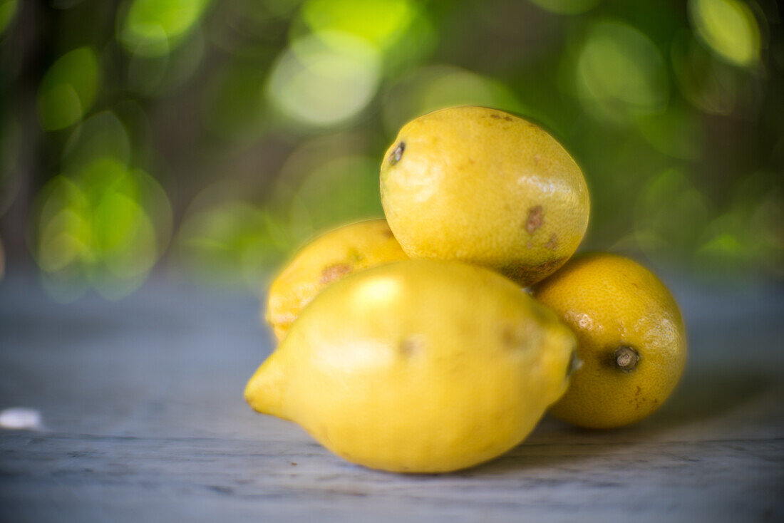 Close up of fresh lemons on a table with a blurred green background. Perfect for food and nature themes.