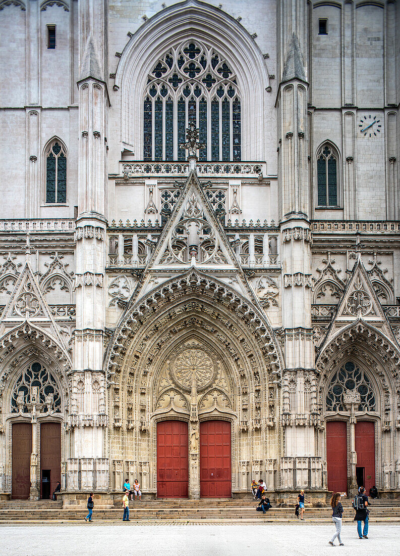 Besucher, die vor der historischen Kathedrale St. Pierre et St. Paul auf dem Platz Saint-Pierre in Nantes, Frankreich, spazieren gehen.