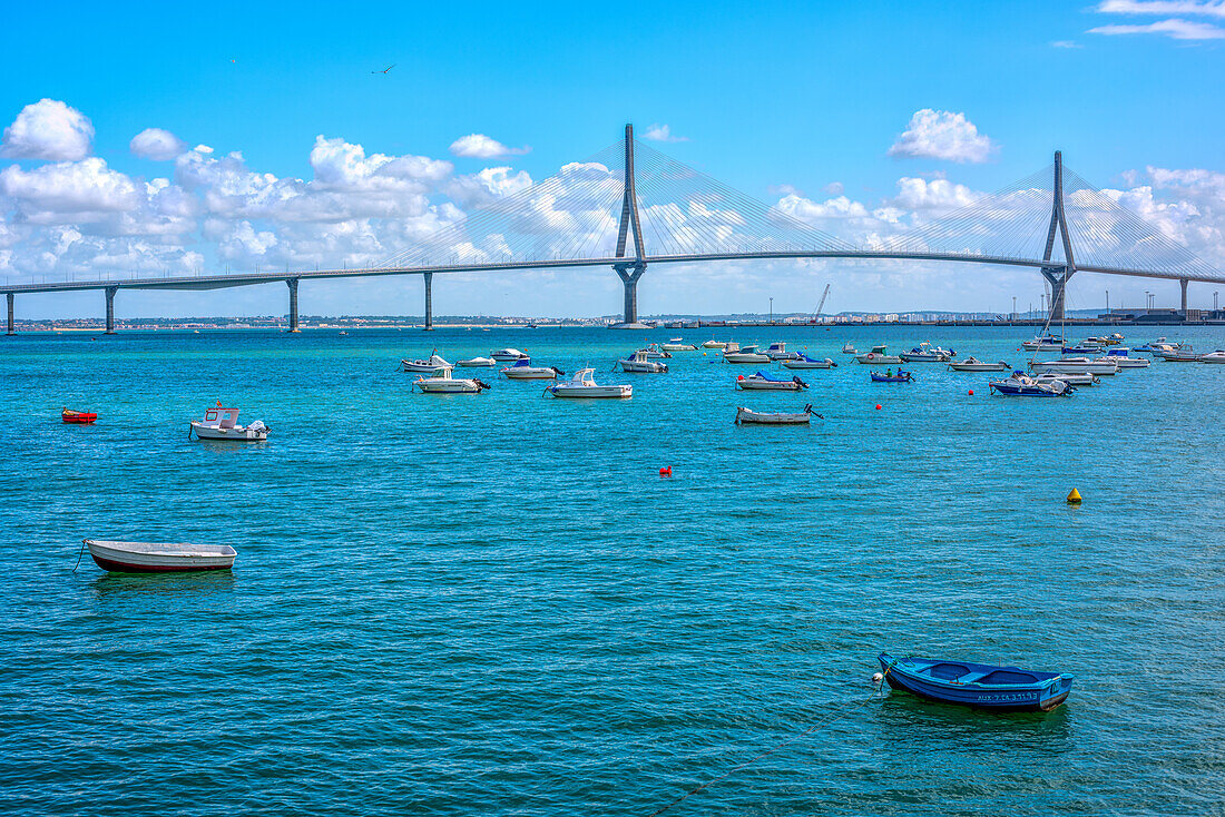 Blick auf schwimmende Boote in der Bucht von Cádiz mit der Brücke über die Verfassung von 1812, auch bekannt als La Pepa-Brücke, im Hintergrund.