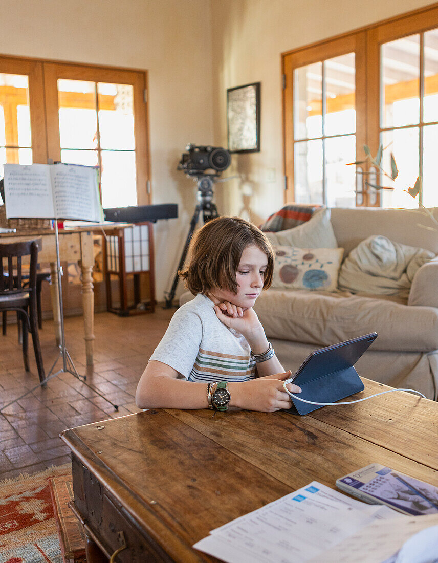 Boy looking at digital tablet at table in living room