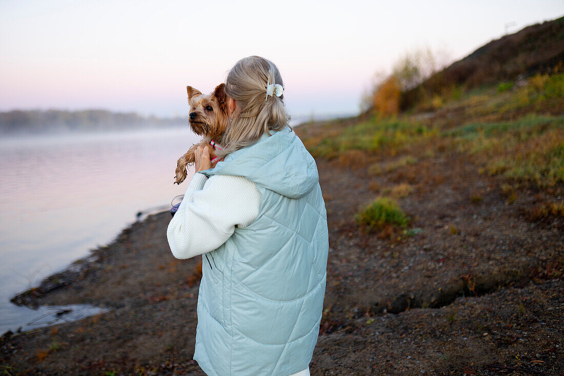 Rückansicht einer Frau mit Yorkshire Terrier am Seeufer