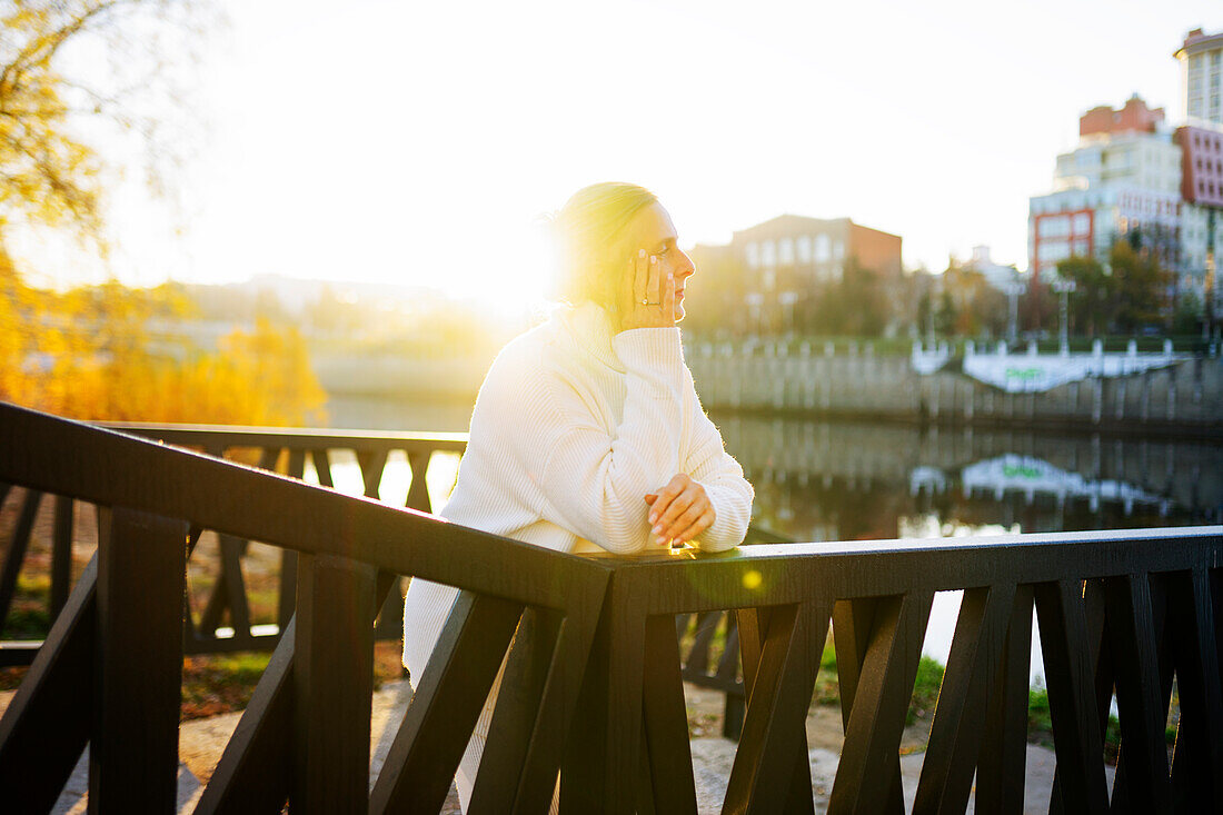 Woman in white sweater leaning on bridge