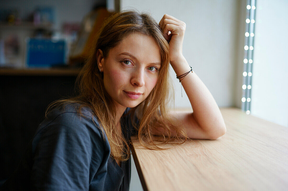 Porträt einer Frau, die sich an ein Fensterbrett lehnt