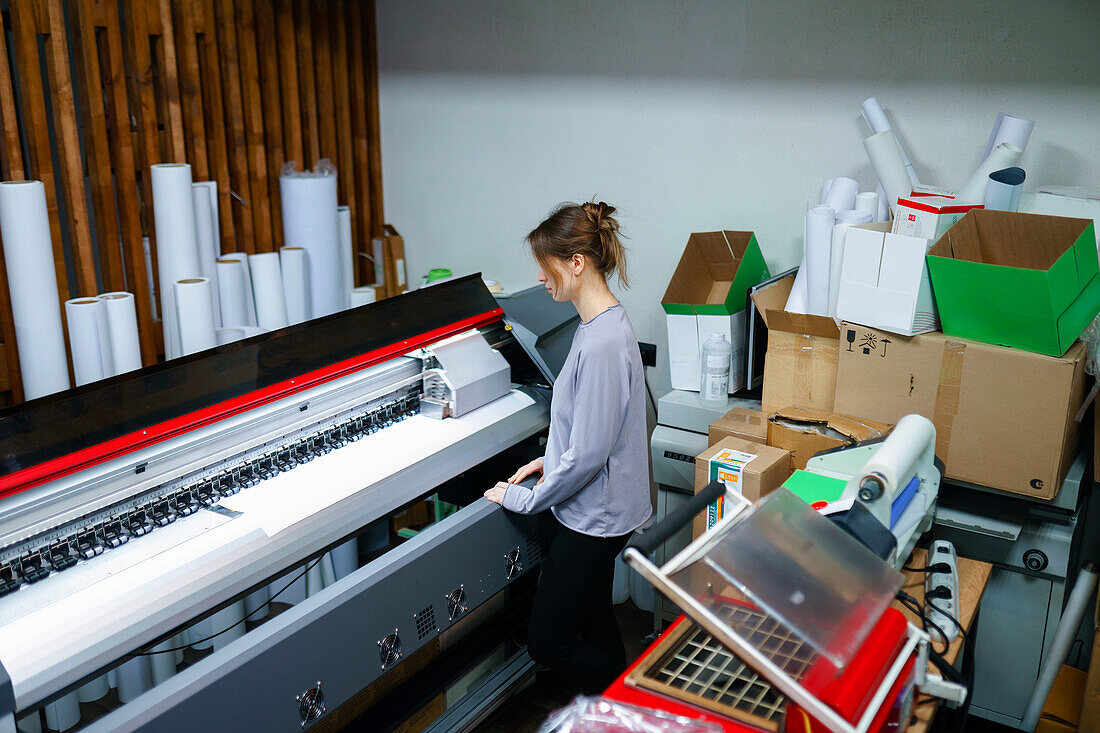 Frau bedient Maschine im Druckatelier