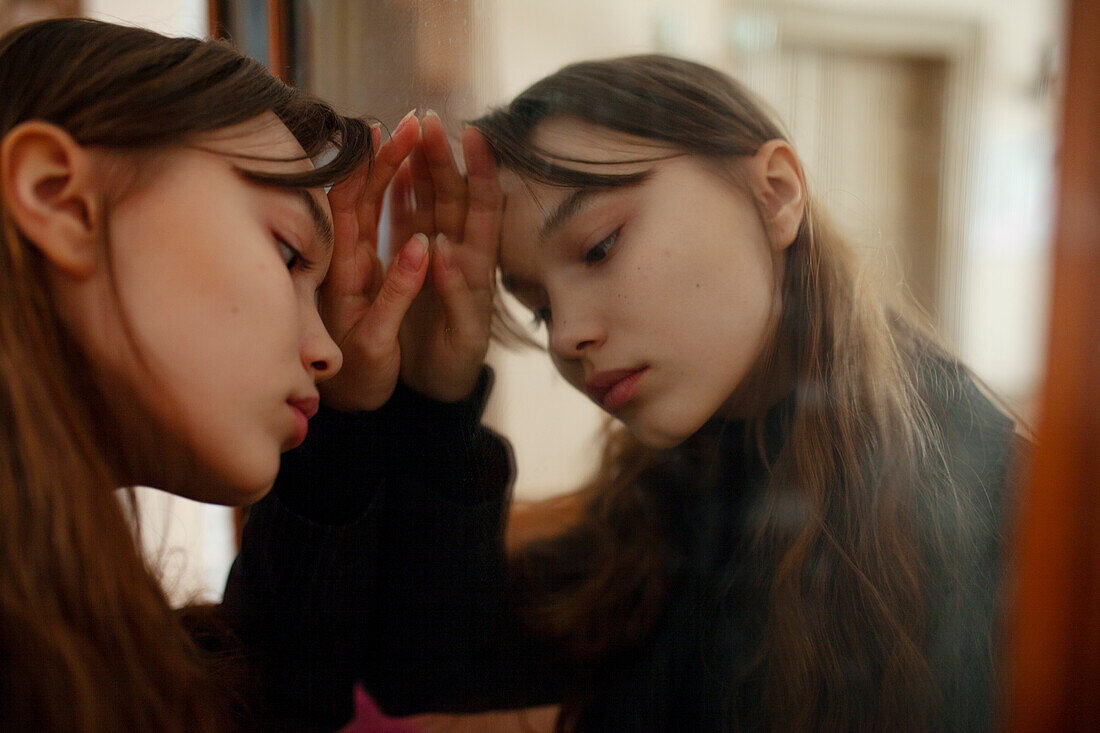 Close-up of pensive young woman leaning against mirror