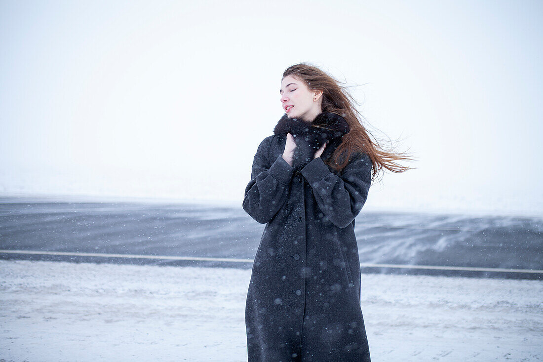 Porträt einer Frau in schwarzem Mantel in einer Winterlandschaft