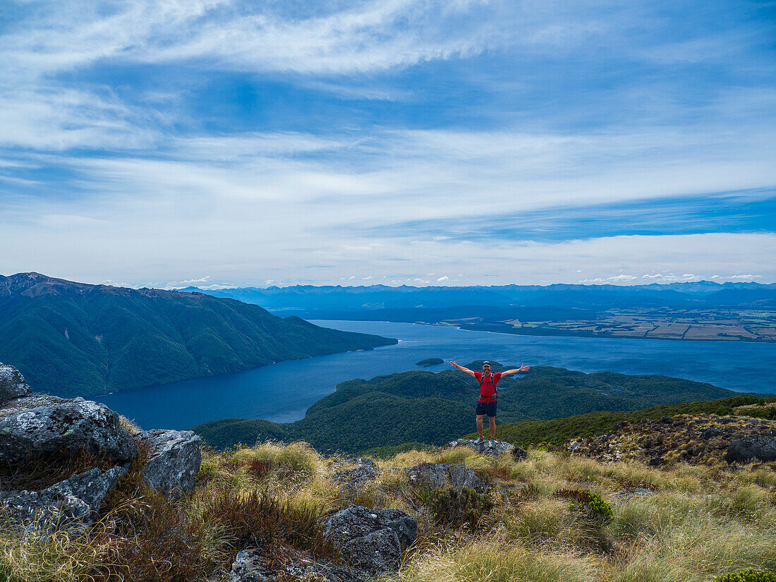 Porträt eines Wanderers mit ausgestreckten Armen im Fiordland-Nationalpark