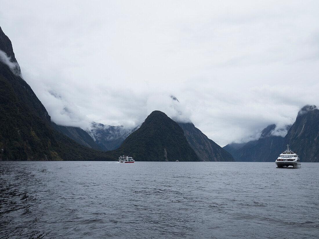 Fähre auf Fjord umgeben von wolkenverhangenen Bergen