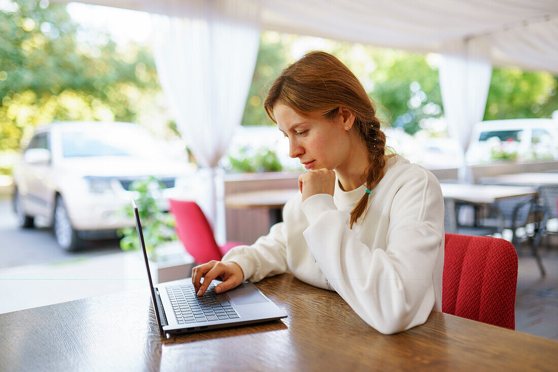 Frau mit Laptop an einem Cafétisch