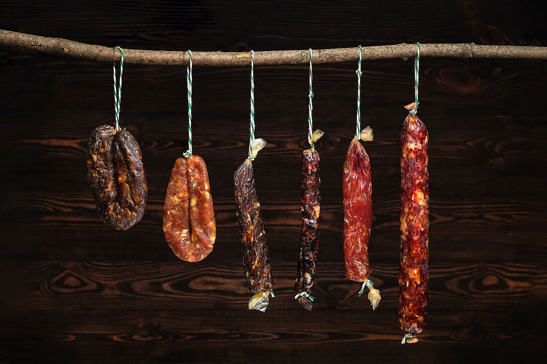 Various dried sausages hanging on a stick