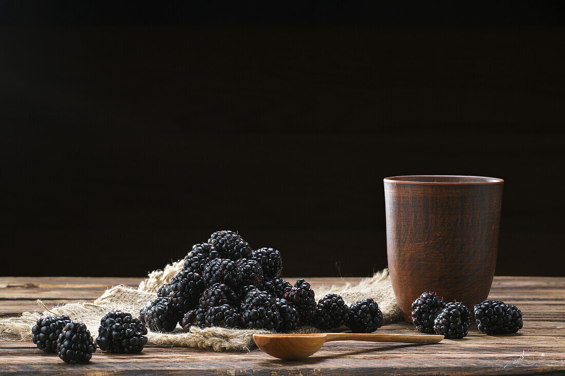 Brombeeren mit rustikalem Tonbecher auf Holztisch