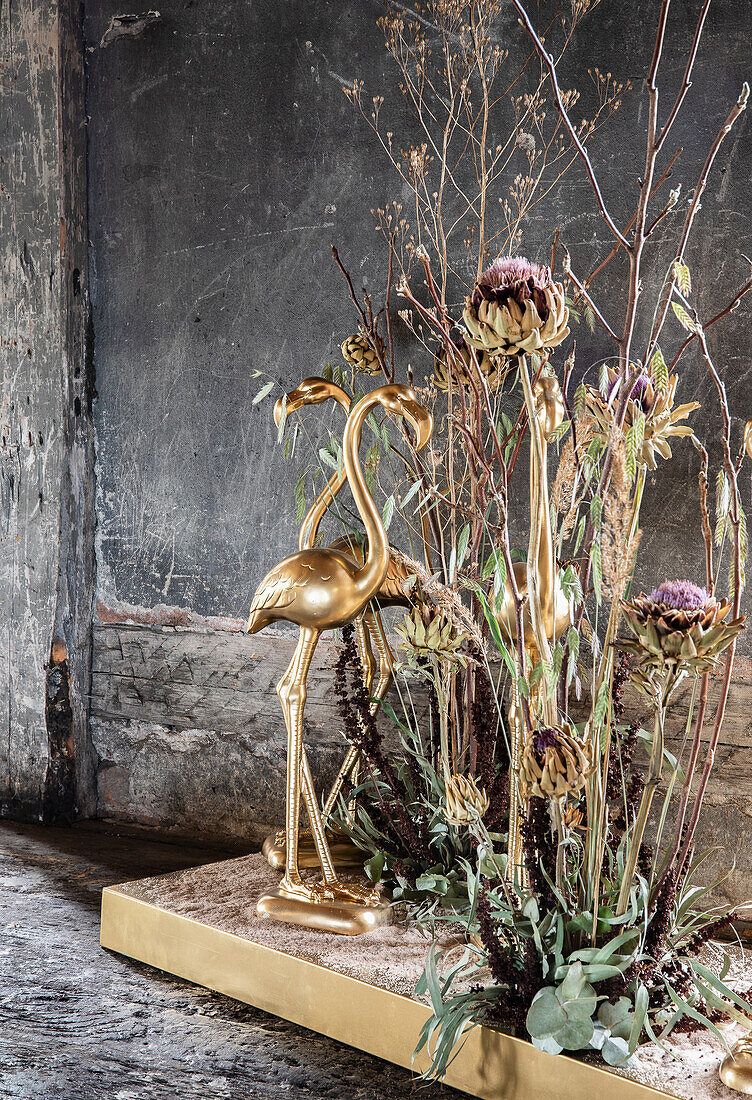 Goldene Flamingo-Skulpturen mit getrockneten Blumen im rustikalen Raum