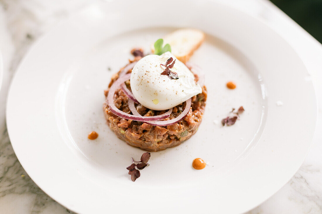 Steak tartare with poached egg and onions