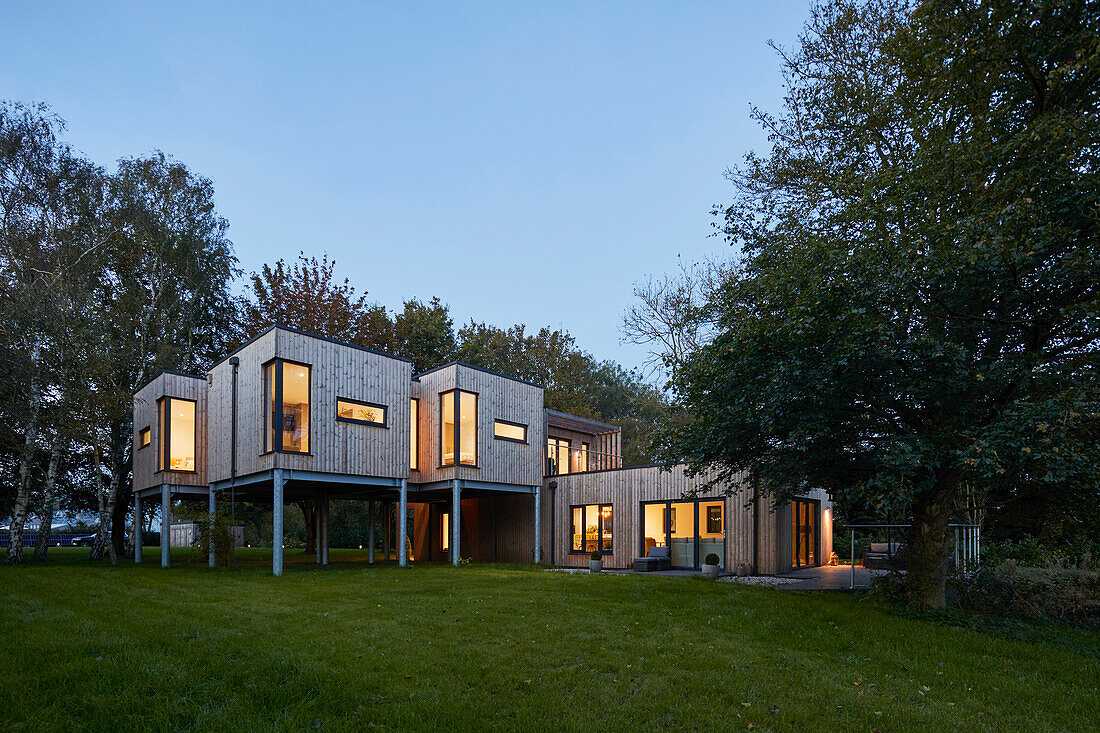 Modernes Holzhaus auf Stelzen bei Dämmerung, Scawby Brook, UK