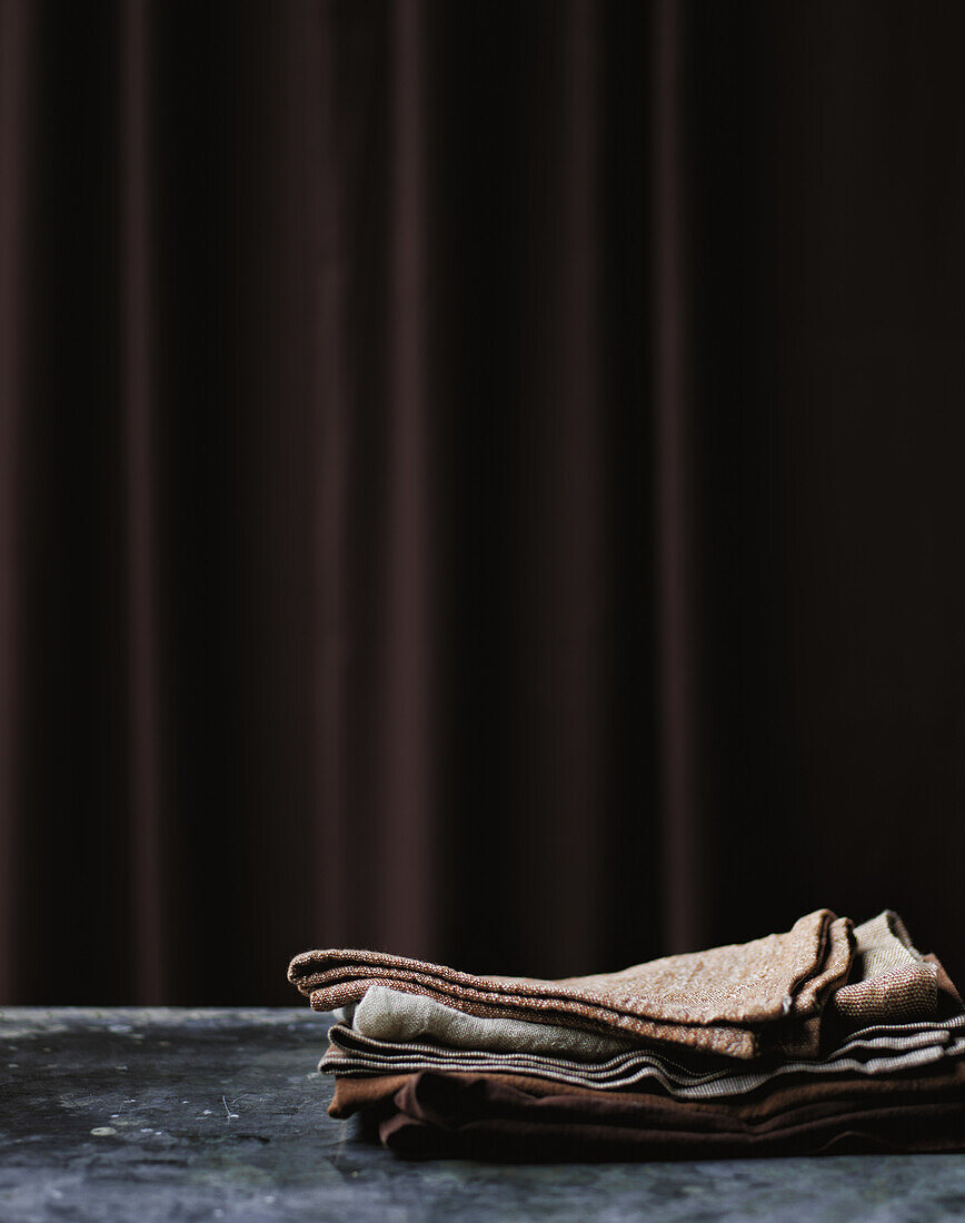 Pile of cloth napkins in front of a brown curtain