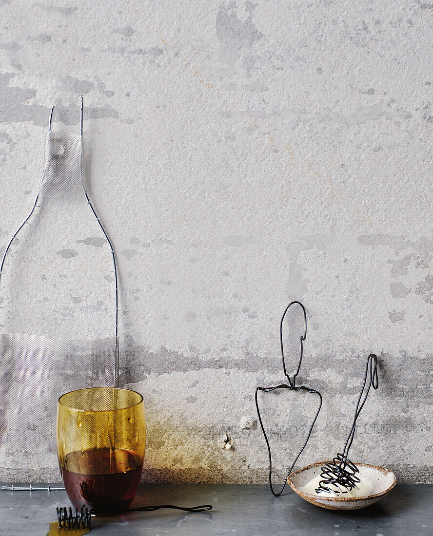 Decorative wire objects and coloured glass against a grey wall