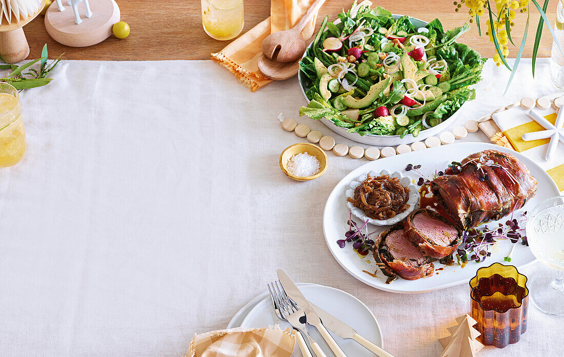 Gebratenes Rindfleisch im Prosciutto-Mantel mit Zwiebelmarmelade und Salat