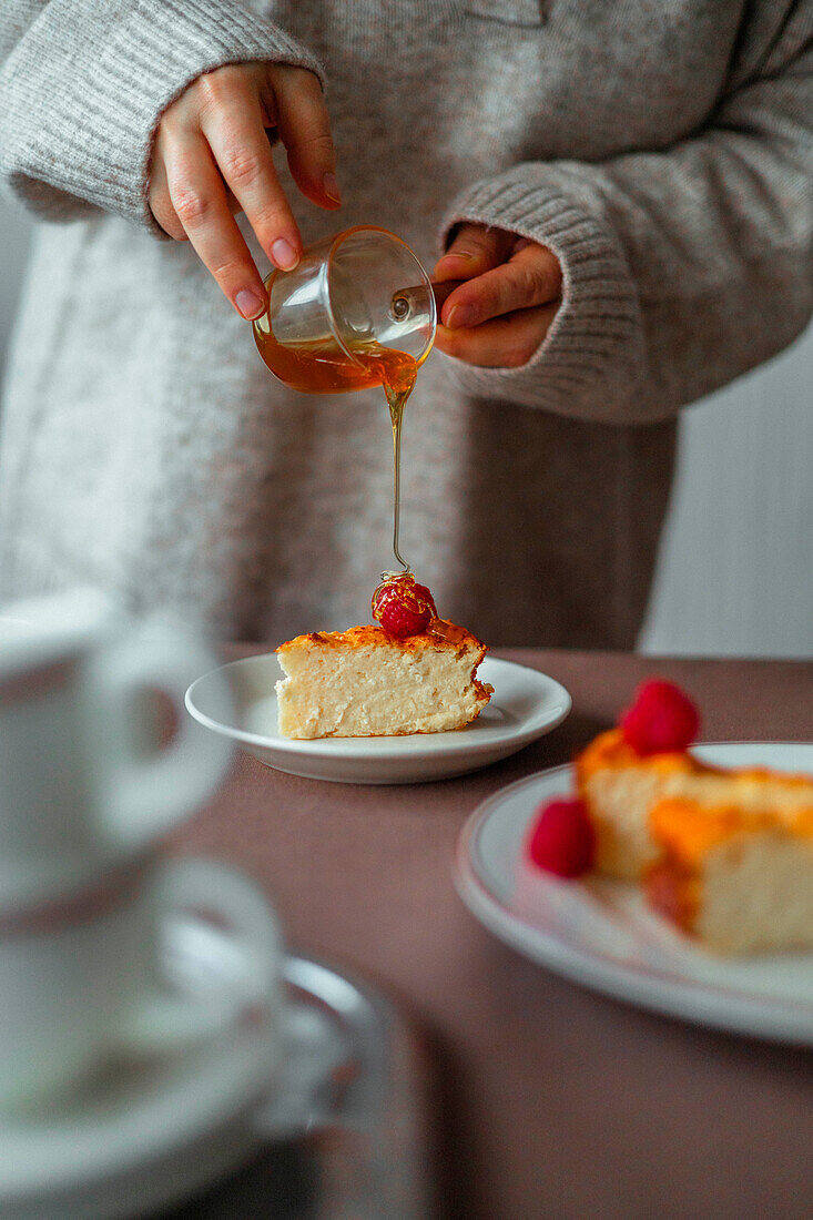 Cheesecake garnished with honey and fresh raspberries