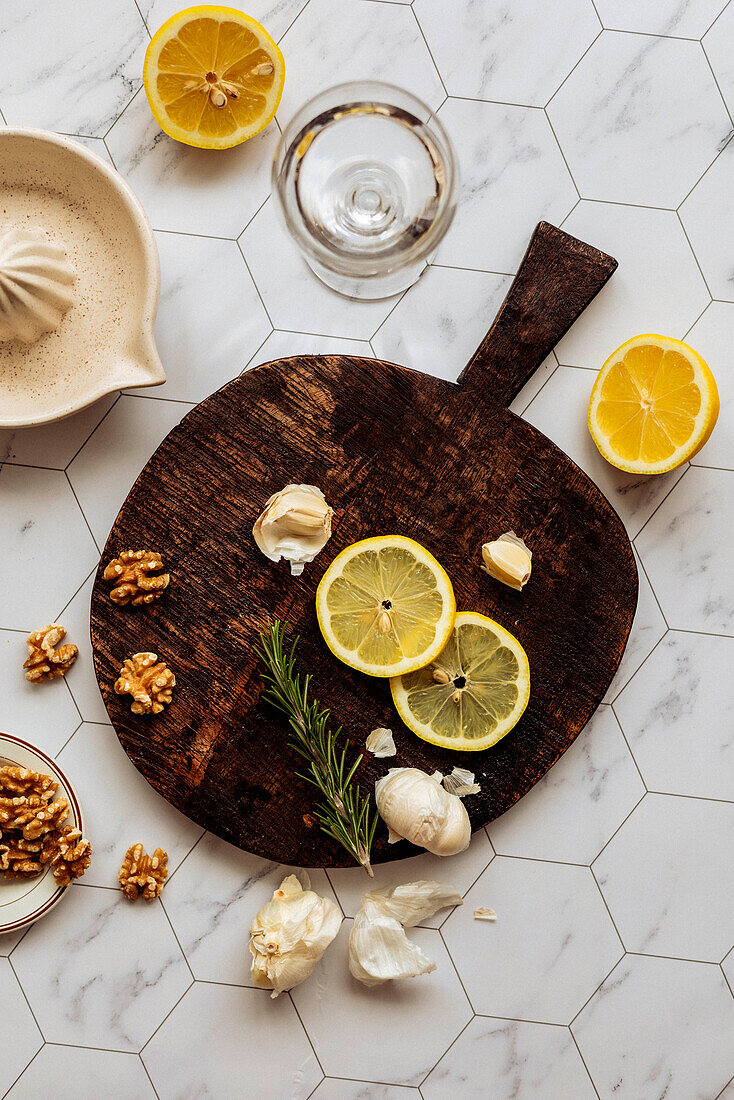 Lemon slices, garlic cloves and walnuts on a wooden board