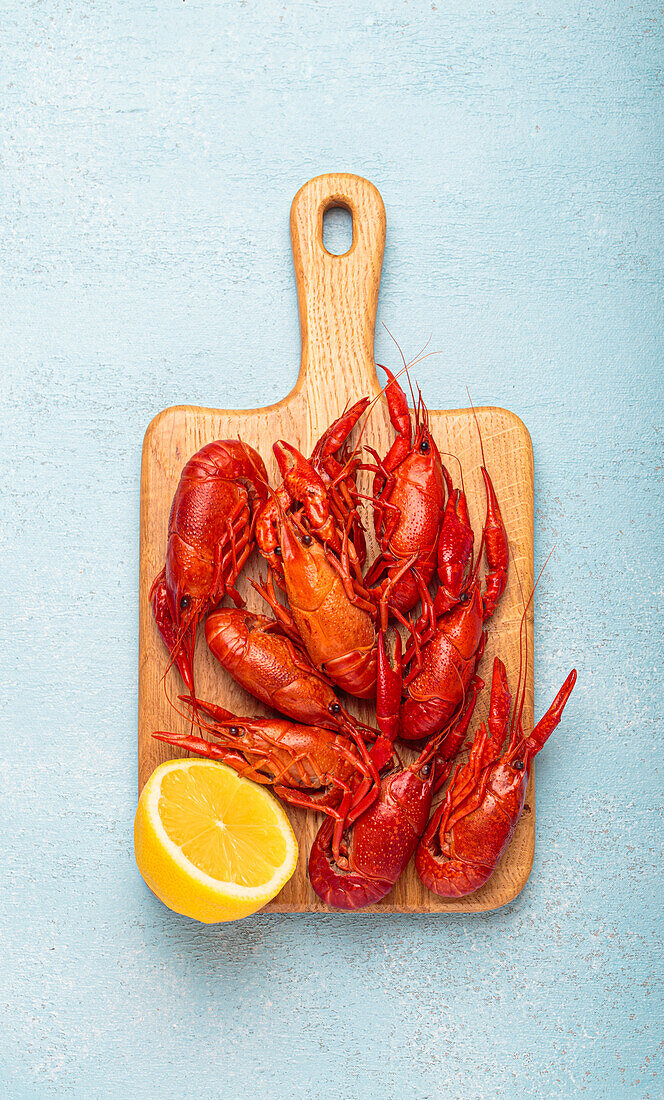 Boiled crayfish with lemon half on a wooden board