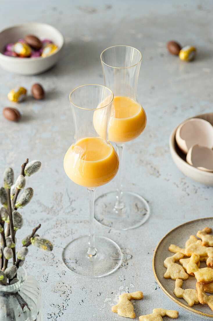 Egg liqueur in a glass next to mini Easter biscuits