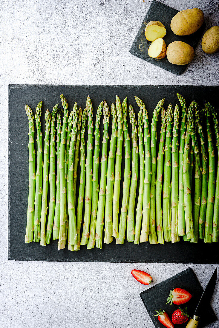 Strung green asparagus with potatoes and strawberries