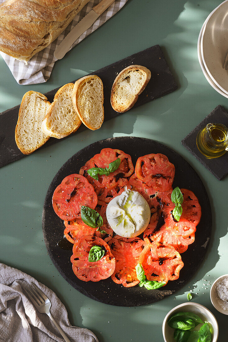 Geschnittene Ochsenherztomaten mit Burrata, Basilikum und Weißbrot