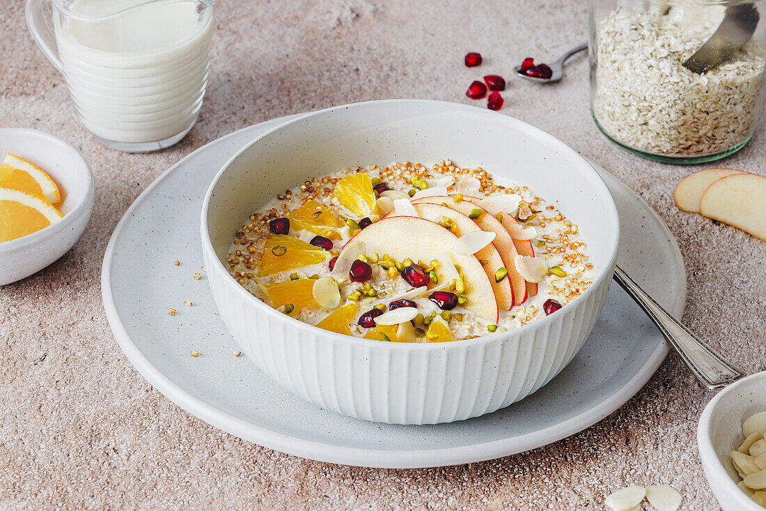 Porridge mit Apfelscheiben, Orange, Granatapfelkernen und Mandeln