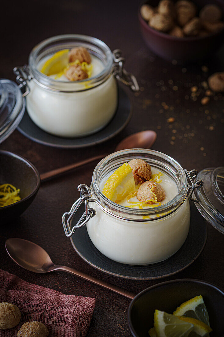 Lemon yoghurt with amarettini biscuits and lemon slices in preserving jars