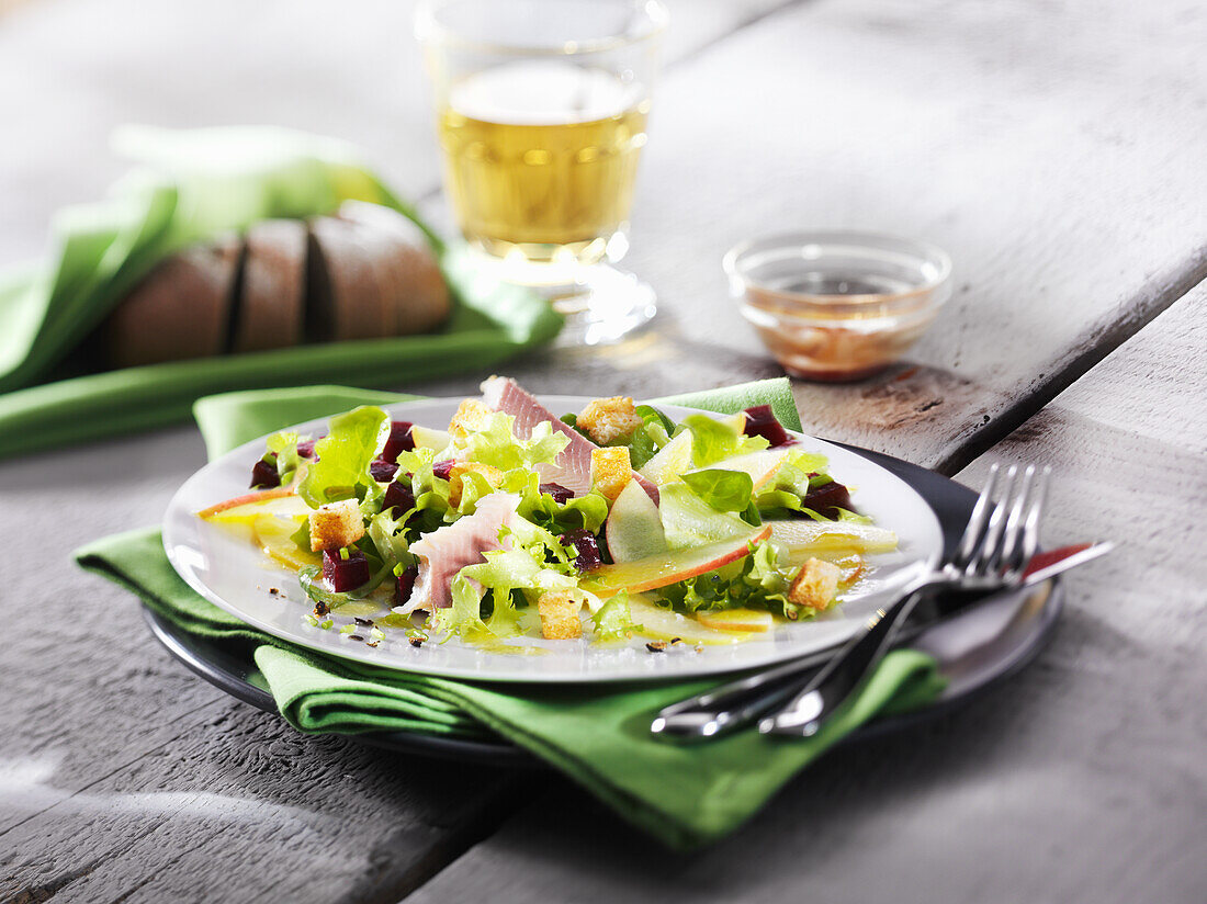 Salad with trout, beetroot, apple slices and croutons