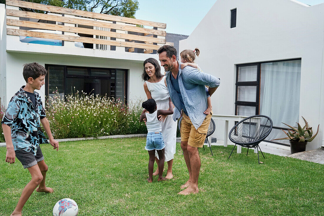 Parents with children playing in backyard