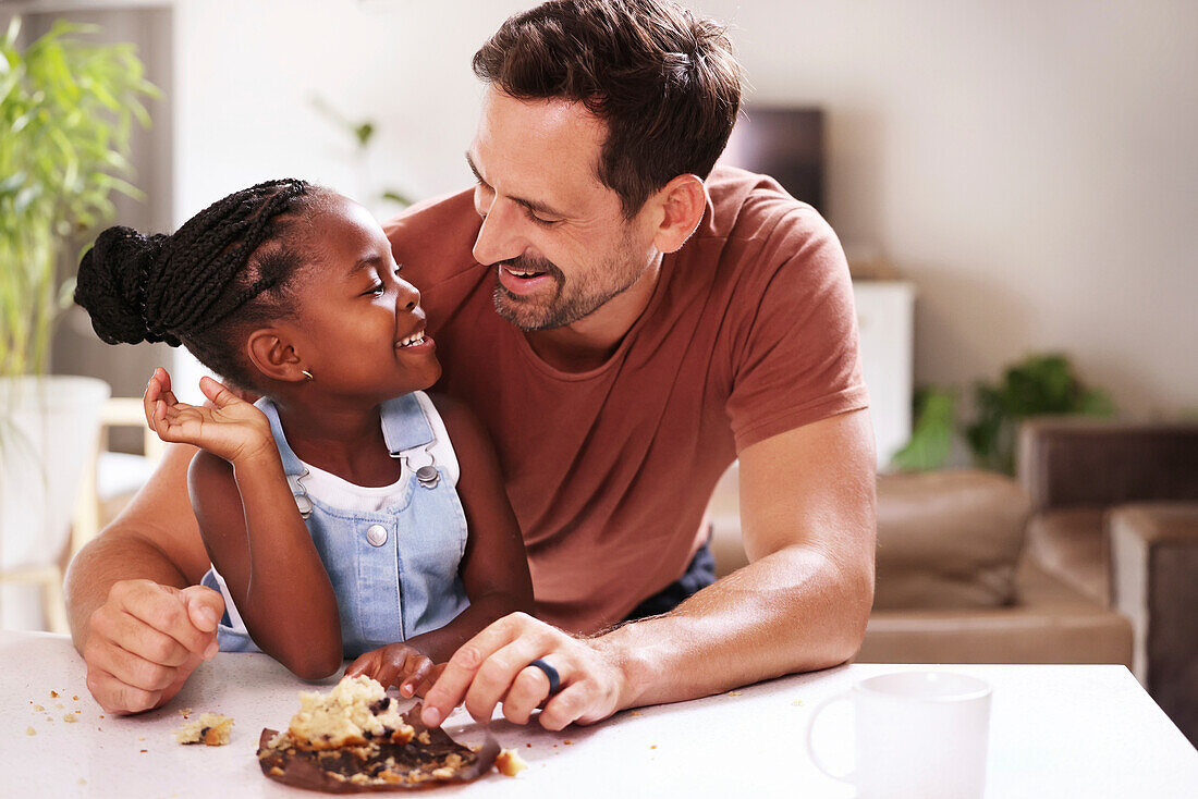 Father embracing smiling daughter at home