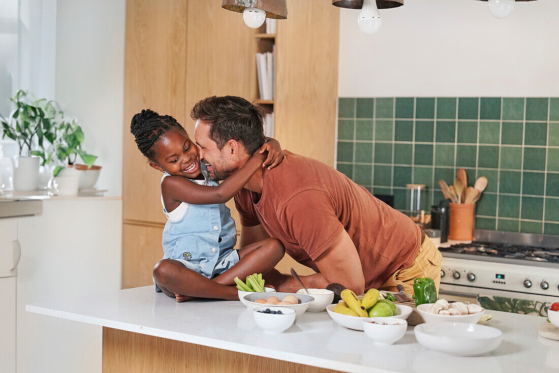 Girl embracing smiling father in kitchen