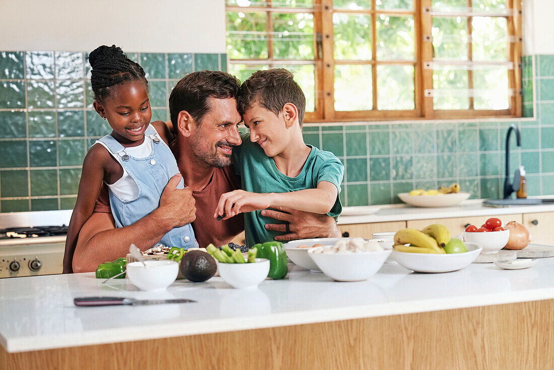 Father embracing children in kitchen