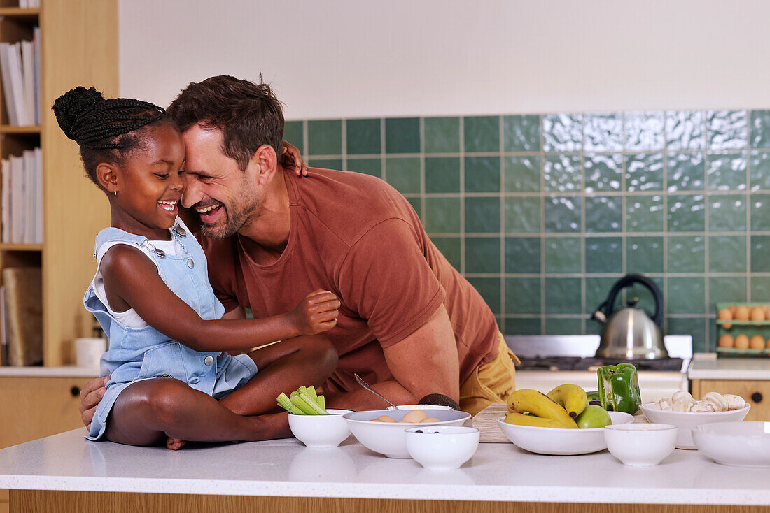 Father embracing smiling daughter in kitchen