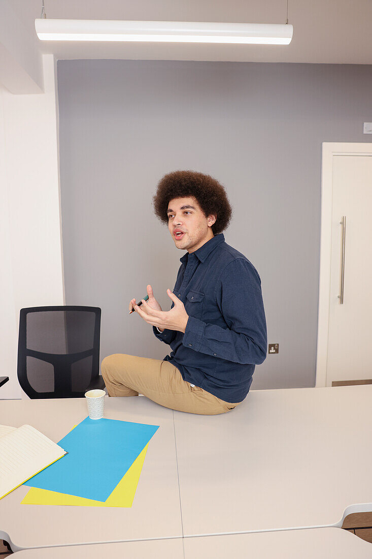 Employee sitting on desk in office