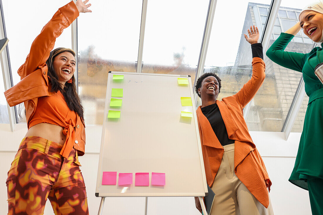 Employees celebrating during team meeting in office