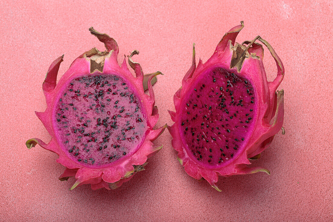 Aufgeschnittene Drachenfrucht auf rosa Hintergrund