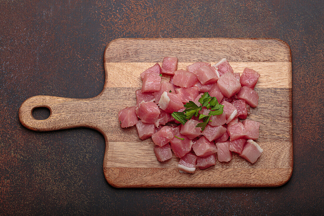 Rohes, gewürfeltes Schweinefleisch auf Holzbrett