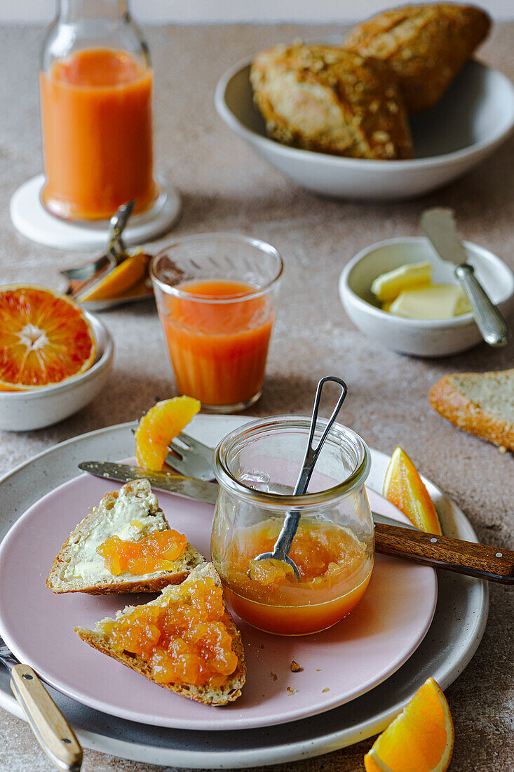 Breakfast with fresh bread rolls, orange marmalade and blood orange juice