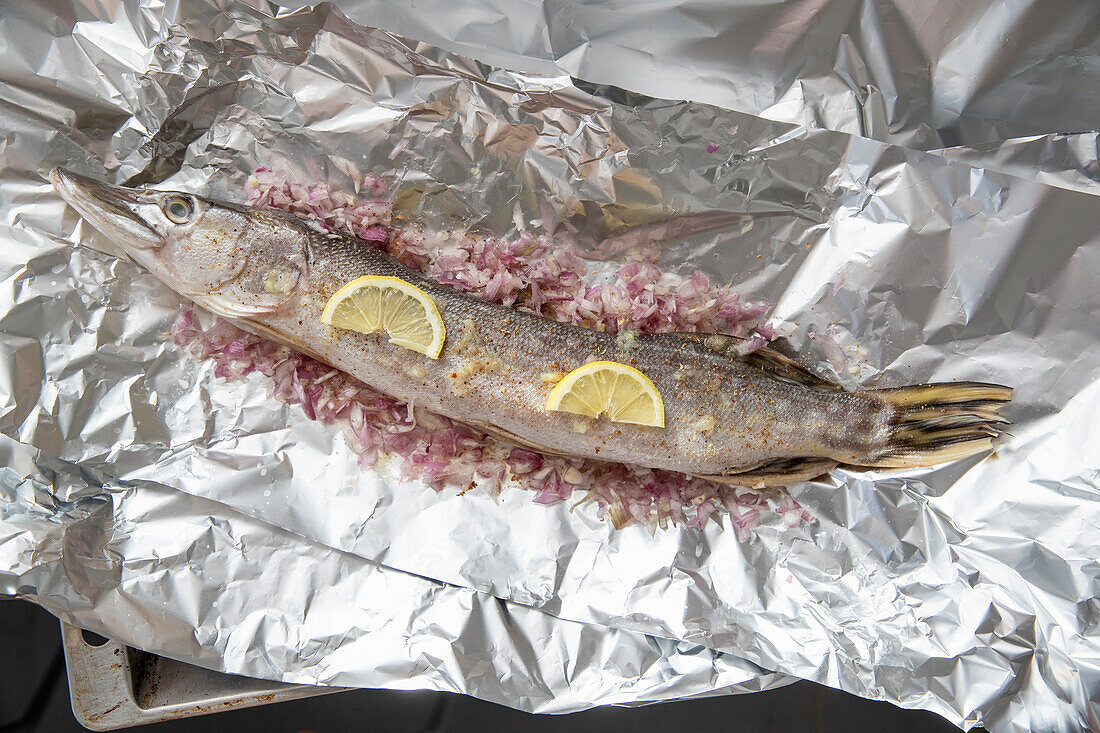 Raw pike with lemon and shallots in aluminium foil