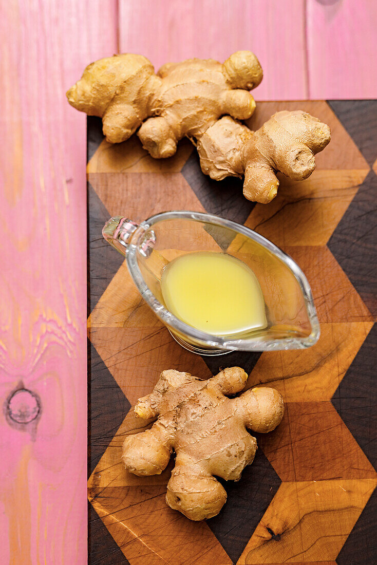 Ginger tubers and ginger essence on a wooden board