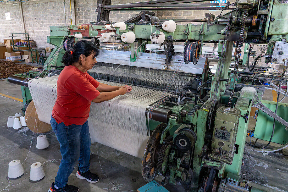 A worker demonstrates the powerloom weaving machine at Hilandería Warmi, a weaving mill in Palpalá, Argentina.