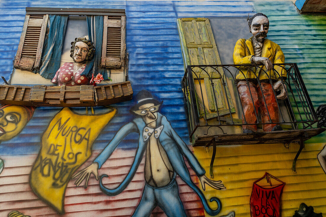 Caricature statues of people with murals on a wall in a shopping arcade in Caminito, La Boca, Buenos Aires, Argentina.