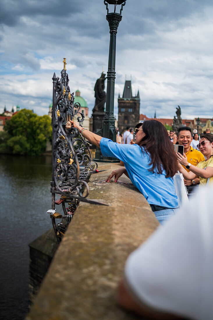 Tourists touching a plaque in Charles Bridge for good luck, Prague.