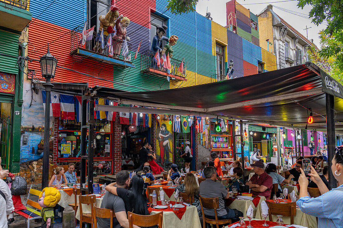 Tourists eat al fresco in a sidewalk cafe and watch tango dancers in Caminito, La Boca, Buenos Aires, Argentina.