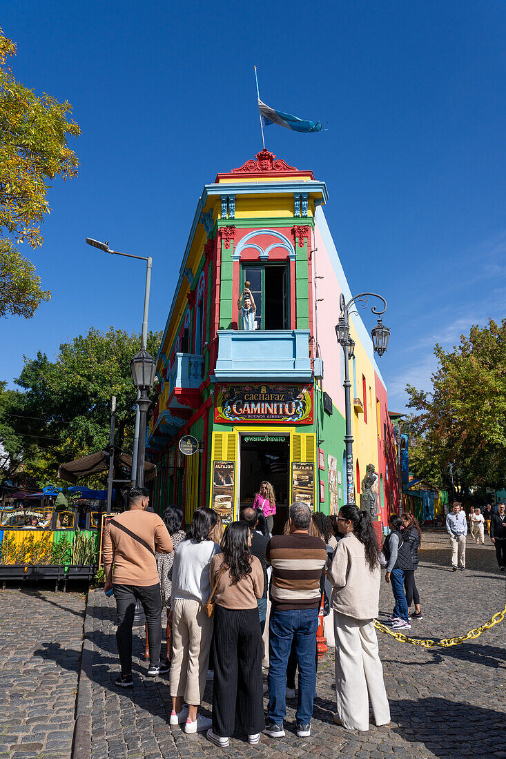 A tourist poses for a photo on Caminito Street in La Boca, Buenos Aires, Argentina.